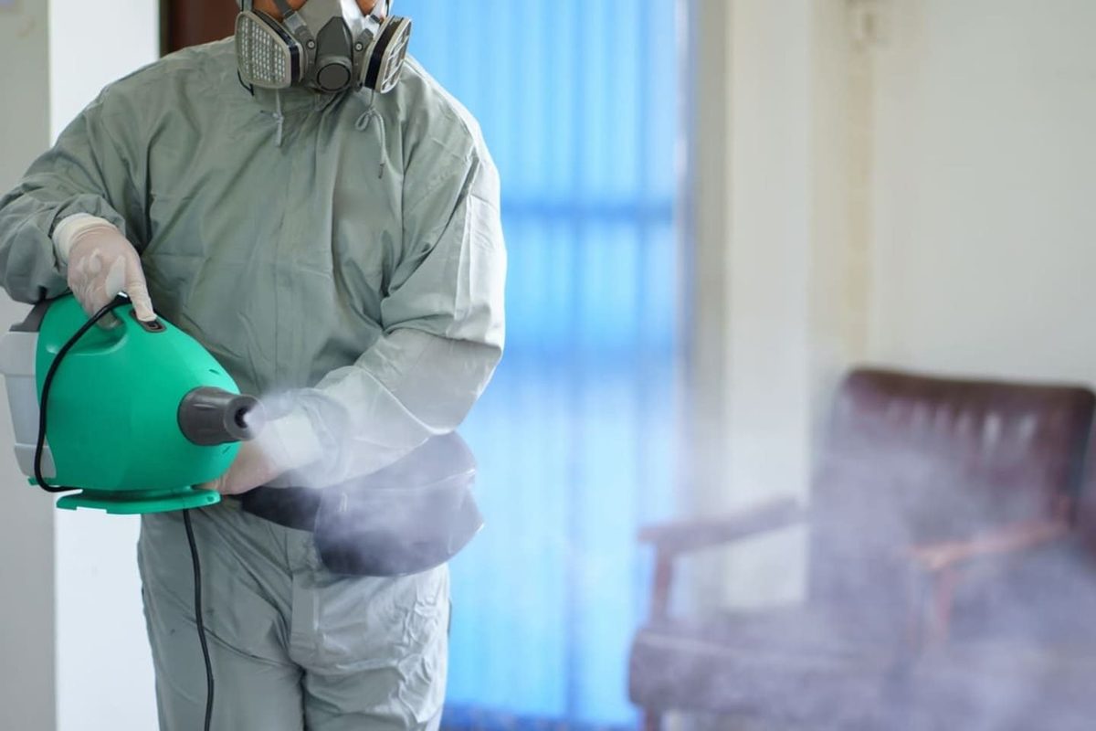 Technician applying disinfectant with an electrostatic sprayer inside a commercial building
